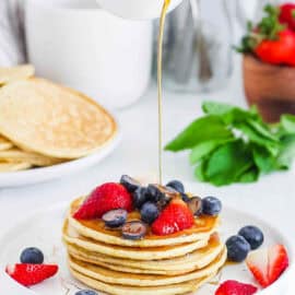 Easy mochi pancakes served with maple syrup and berries on a white plate.