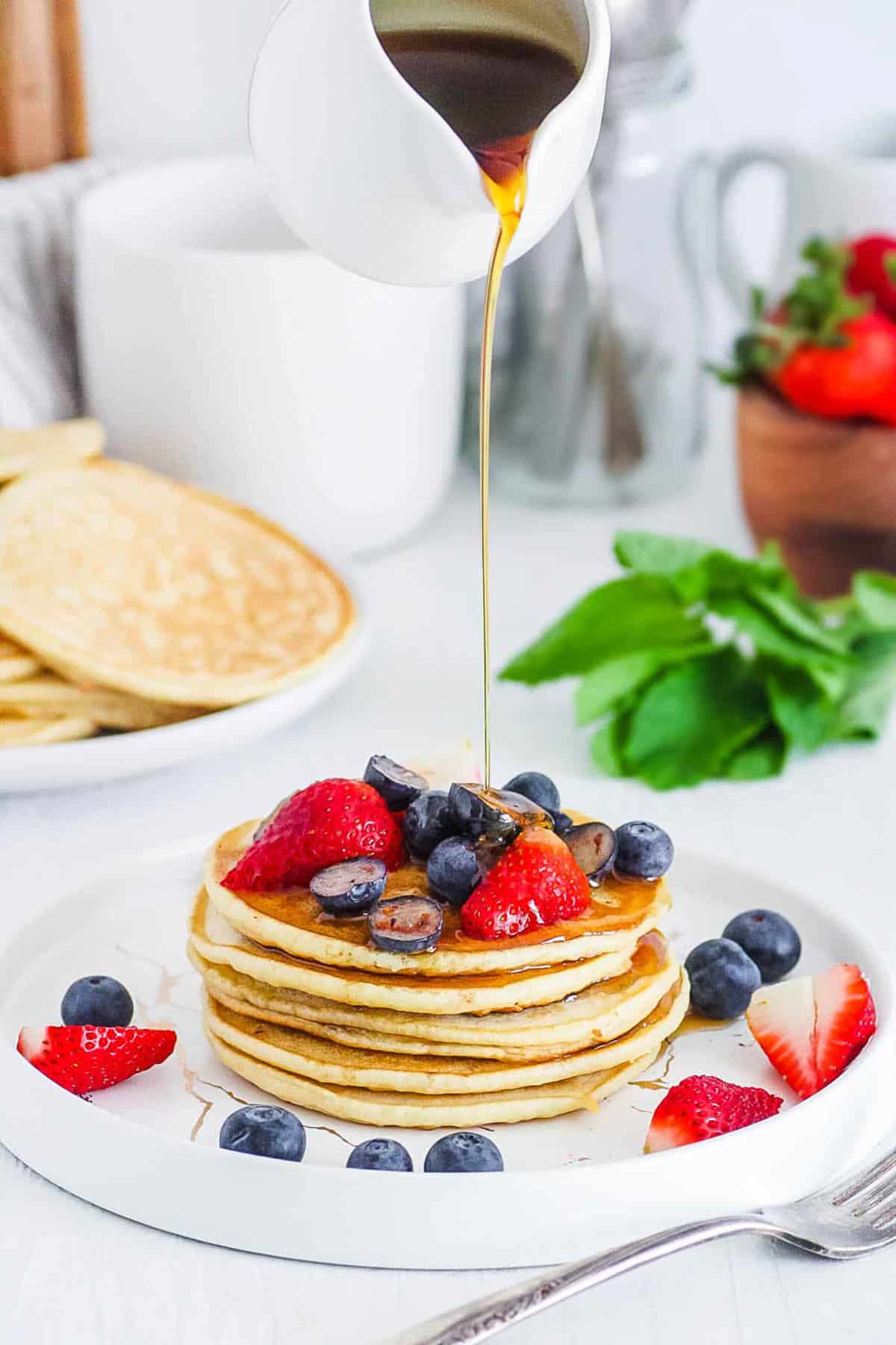 Easy mochi pancakes served with maple syrup and berries on a white plate.