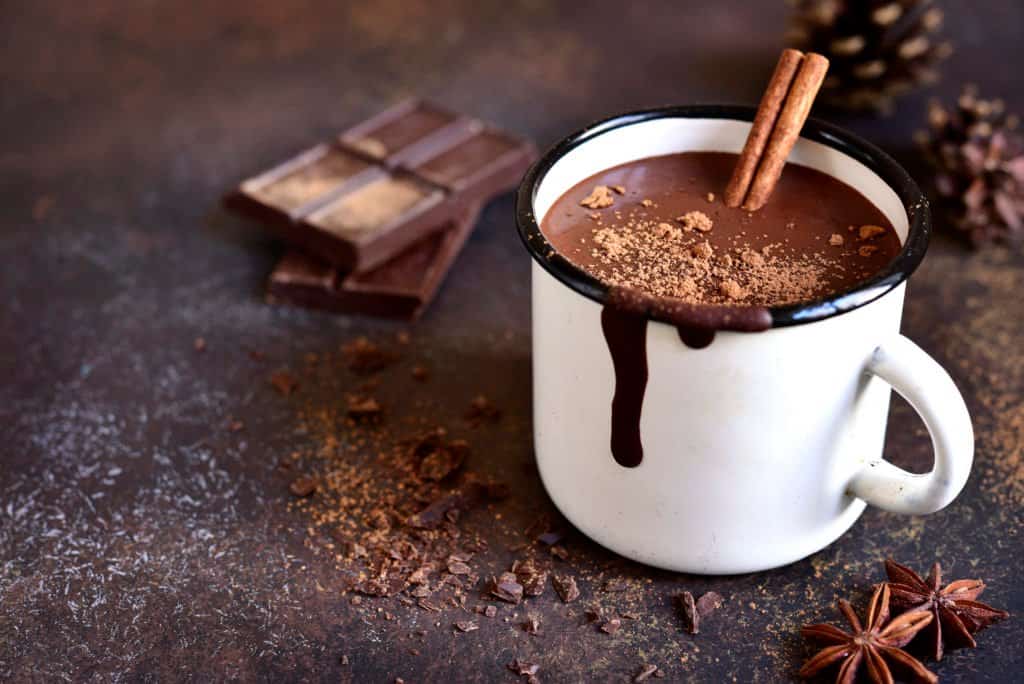 Xocolatl - Homemade spicy hot chocolate with cinnamon in enamel mug on a slate,stone or concrete background.