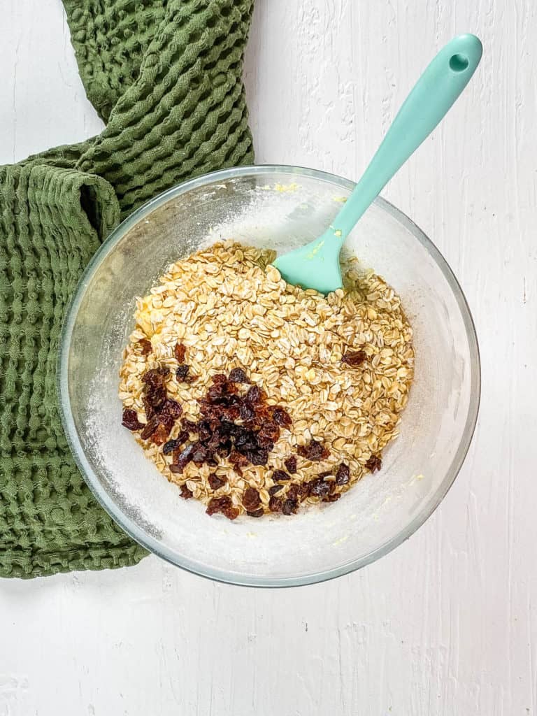 oats and raisins combined with dry ingredients in a bowl