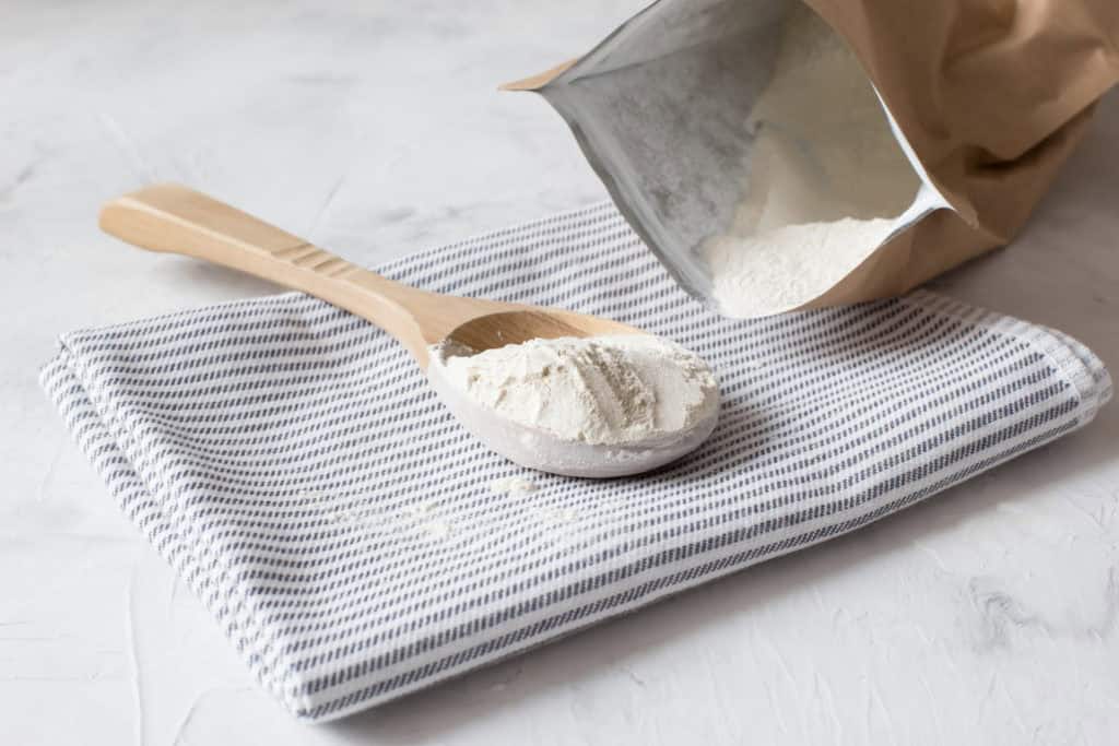 Crumbly xanthan gum in a wooden spoon. Natural thickening agent used in cooking.