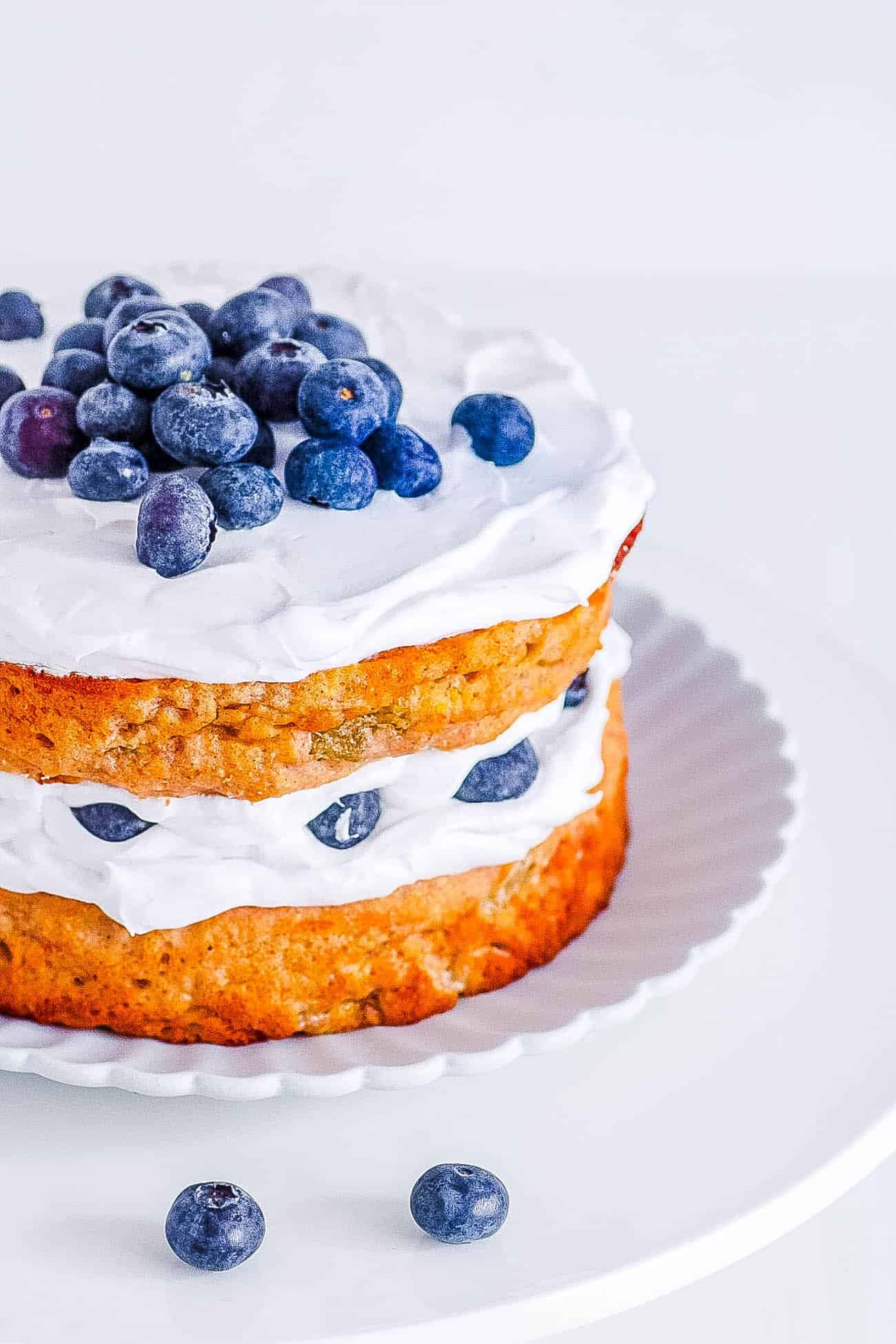 A healthy smash cake decorated with blueberries on a white plate.
