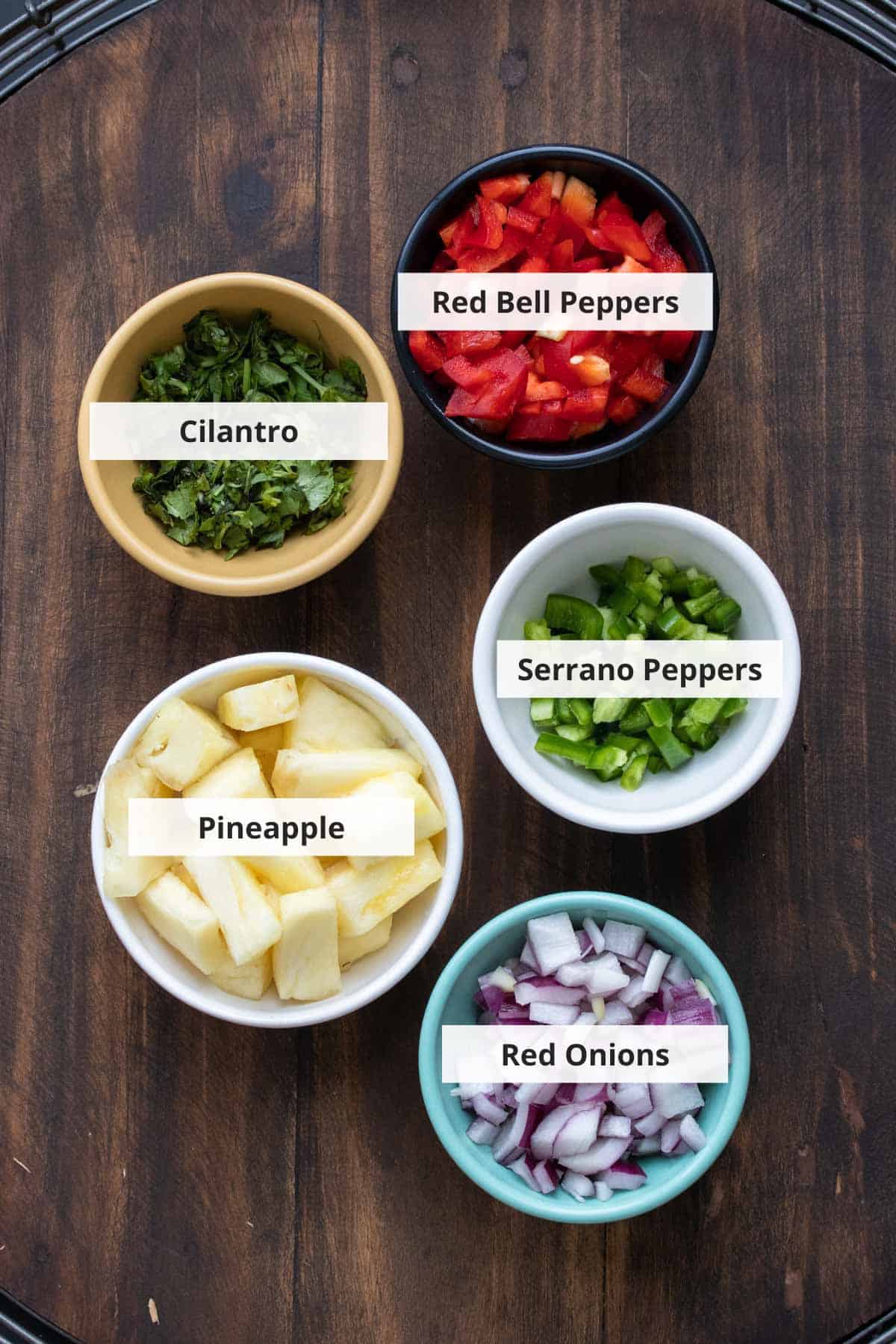 Ingredients for pineapple salsa, on a wood background.