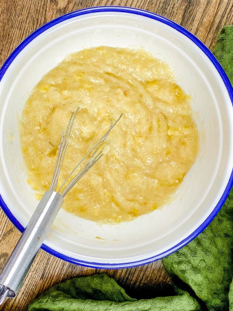 Whisking applesauce in a large white and blue mixing bowl.