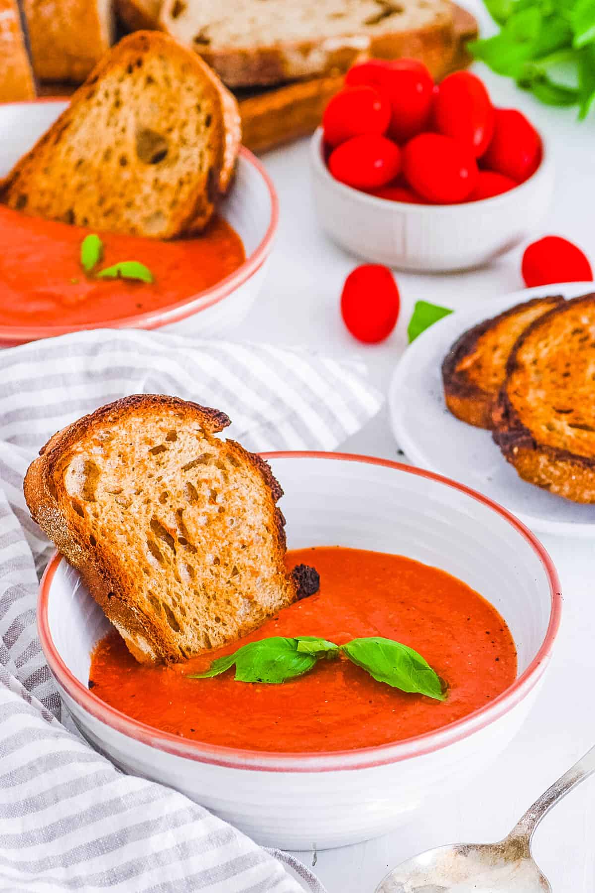best easy healthy homemade vegan tomato soup recipe in a bowl with basil and crusty bread