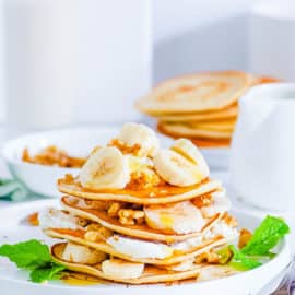 easy healthy plant based egg free vegan protein pancakes recipe topped with banana on a white plate