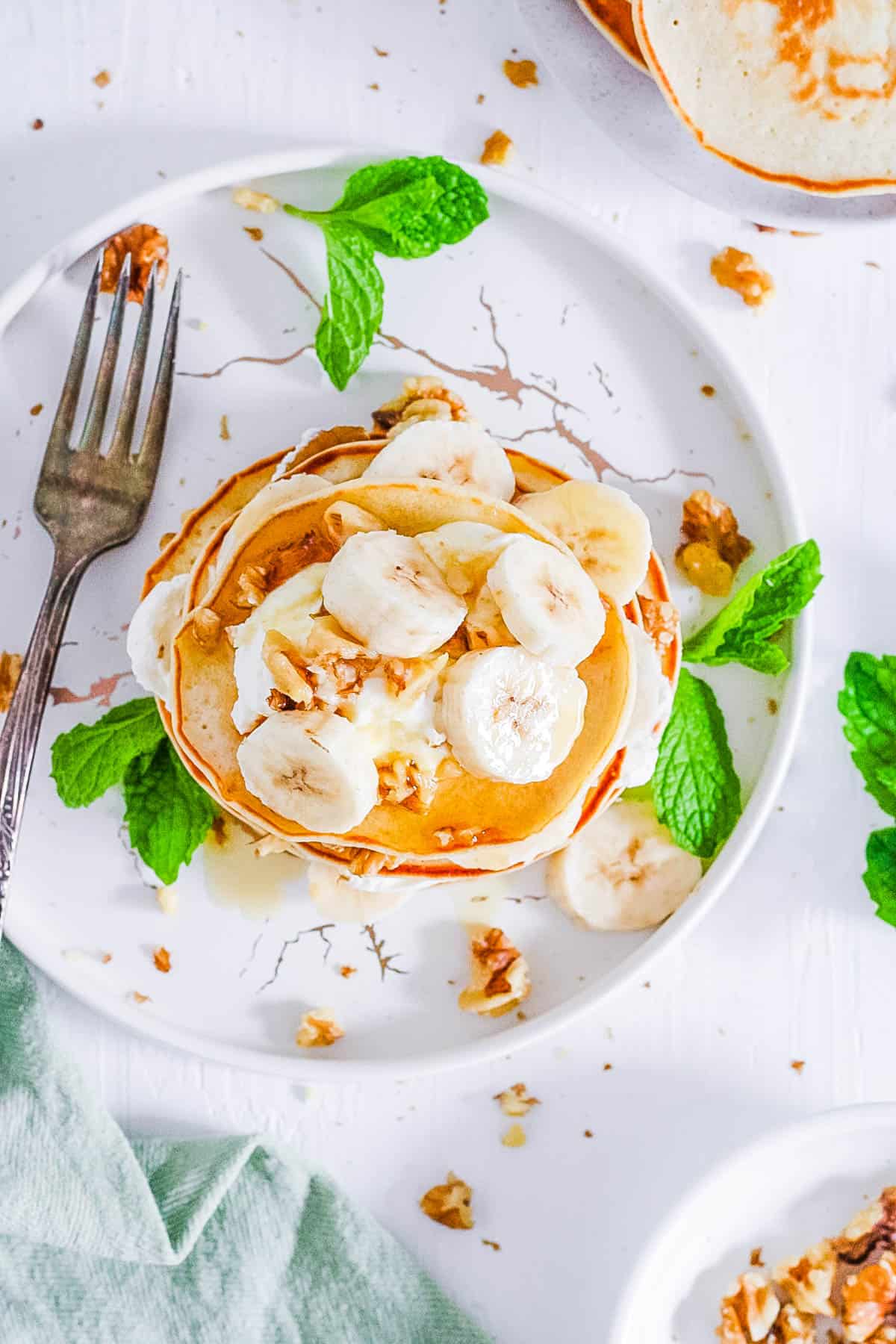 easy healthy vegan protein pancakes recipe topped with banana on a white plate