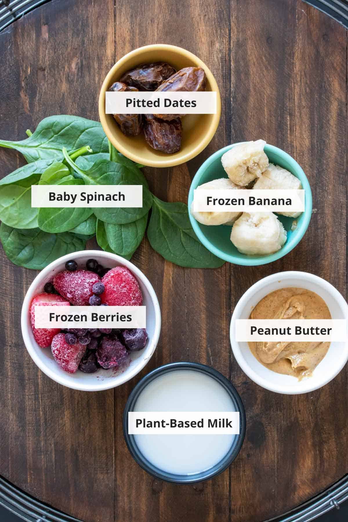 Ingredients for a vegan pb&j smoothie recipe on a wood background.