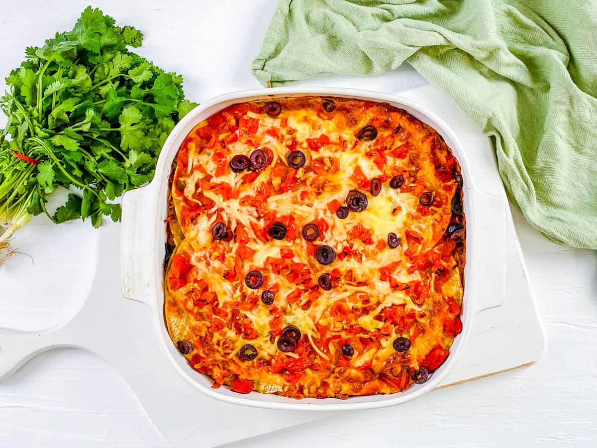 baked easy healthy vegetarian layered taco casserole with tortillas in a white baking dish