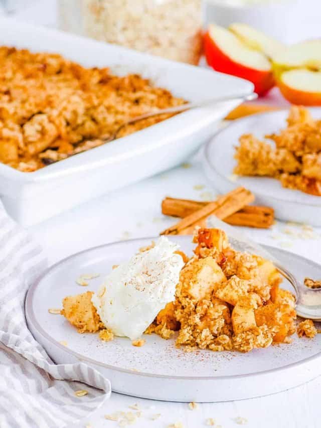 A scoop of vegan apple crumble with ice cream in front of a pan of the crumble.