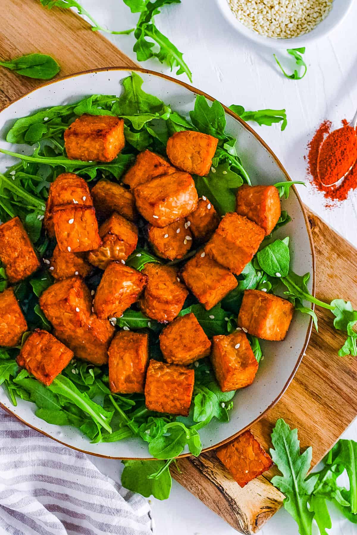 Crispy air fryer tempeh on a white plate with greens.