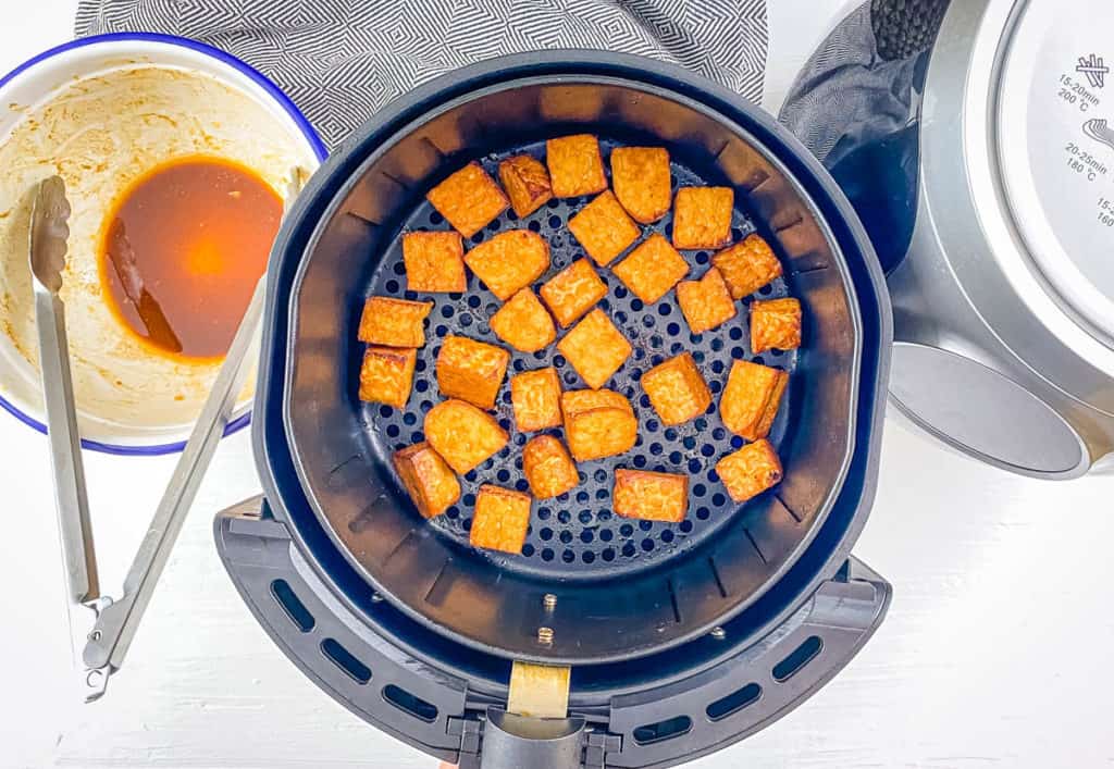 Air fried tempeh in the air fryer basket.