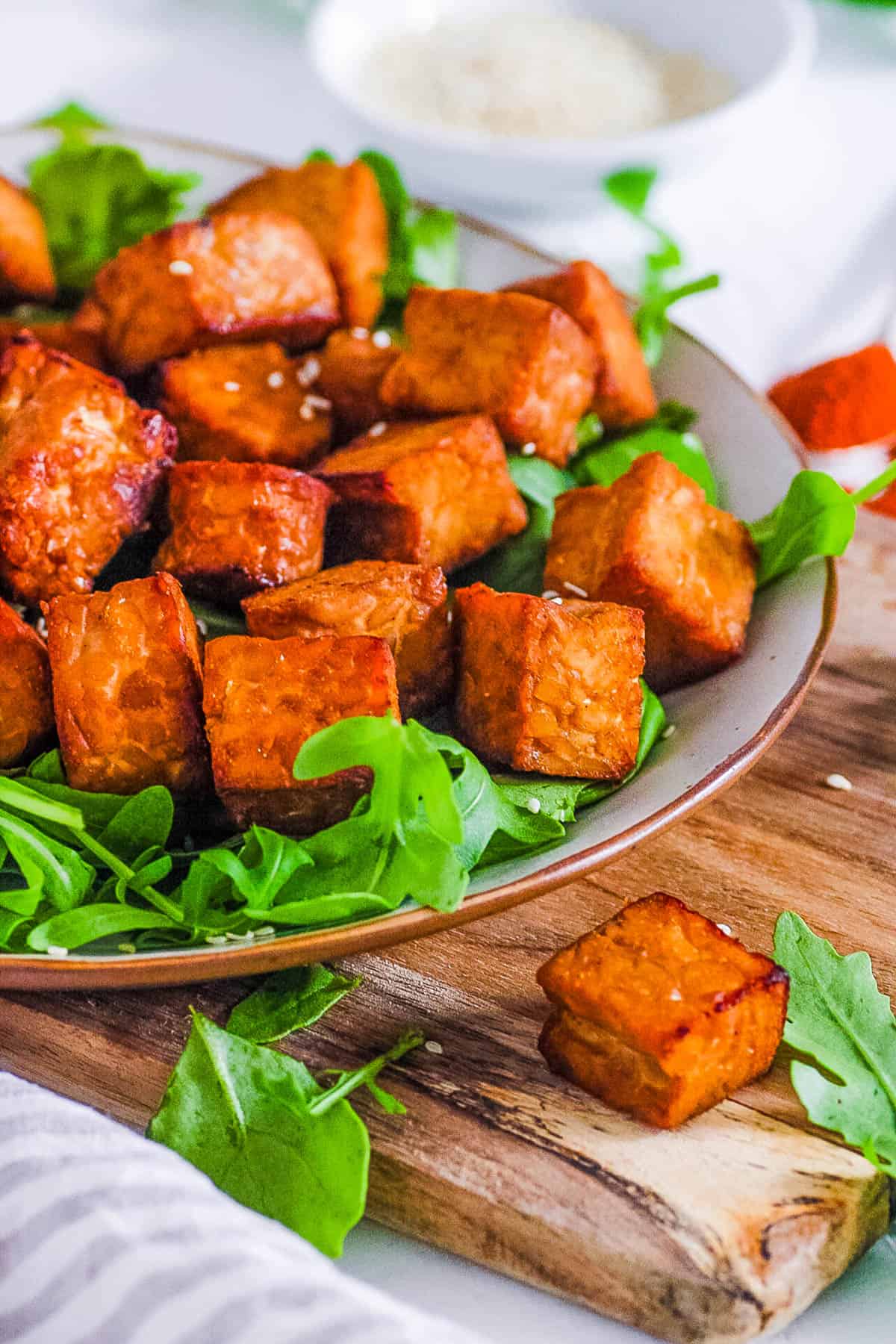 Crispy air fryer tempeh recipe on a white plate with greens. 