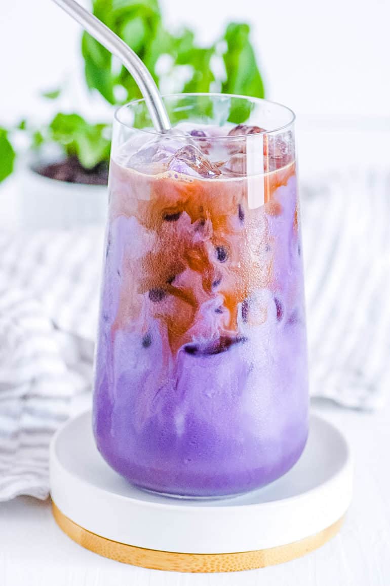 iced ube latte in a glass with a straw