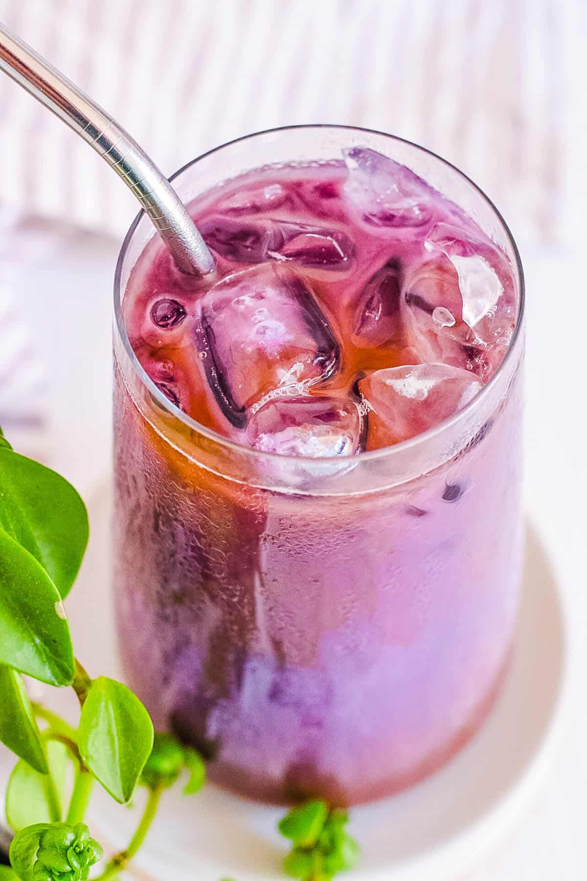iced ube latte (purple yam latte) in a glass with a straw