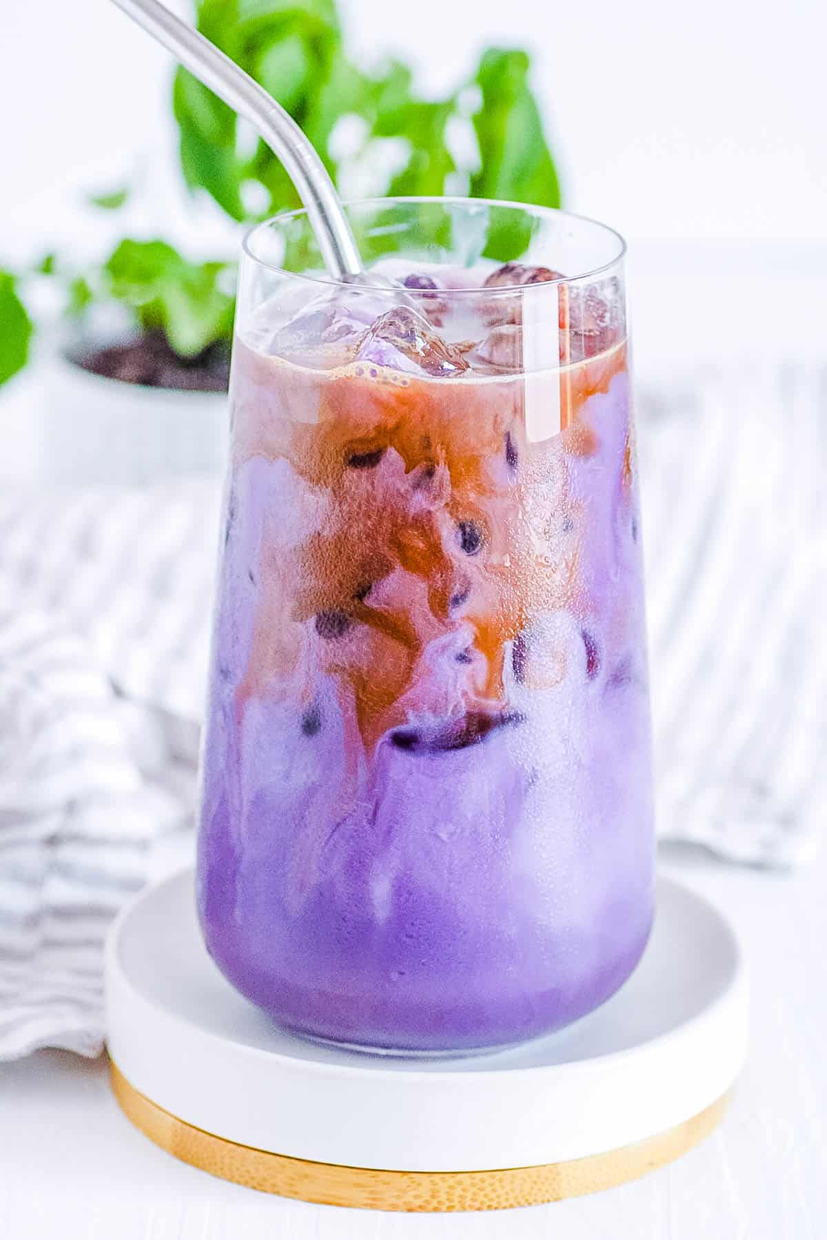 Iced ube latte in a glass with a straw.