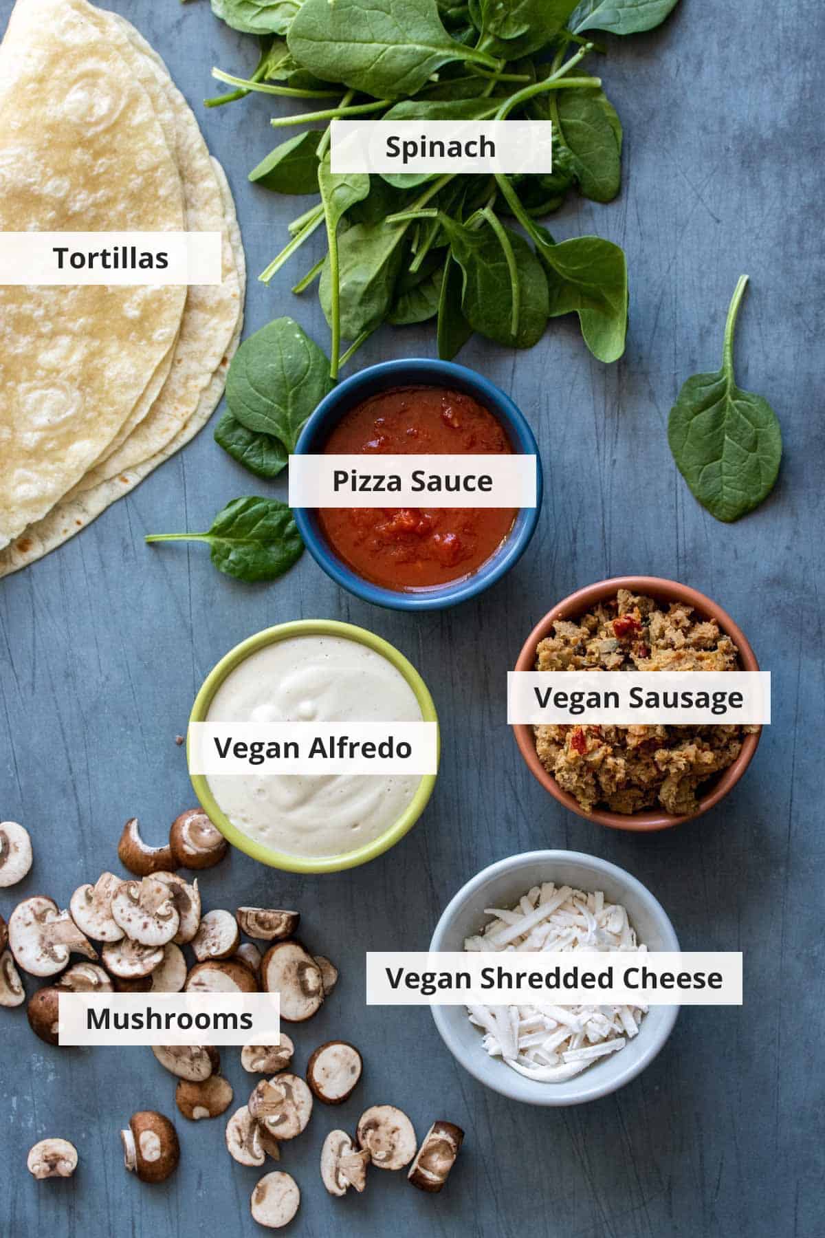 Ingredients for vegan pizza burritos on a grey background.