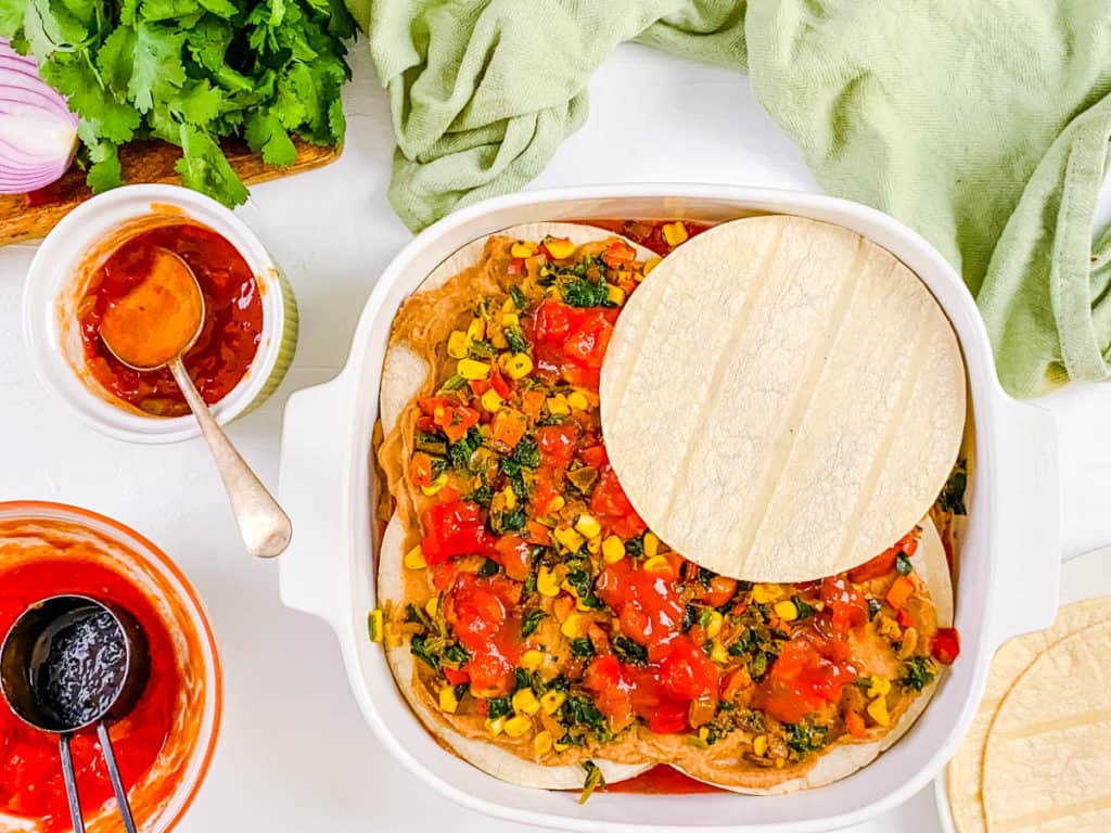 tortillas and veggies layered in a baking dish