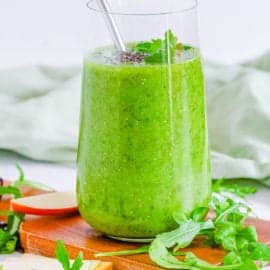 easy, healthy, vegan arugula smoothie with banana, apples and mango in a glass with a straw