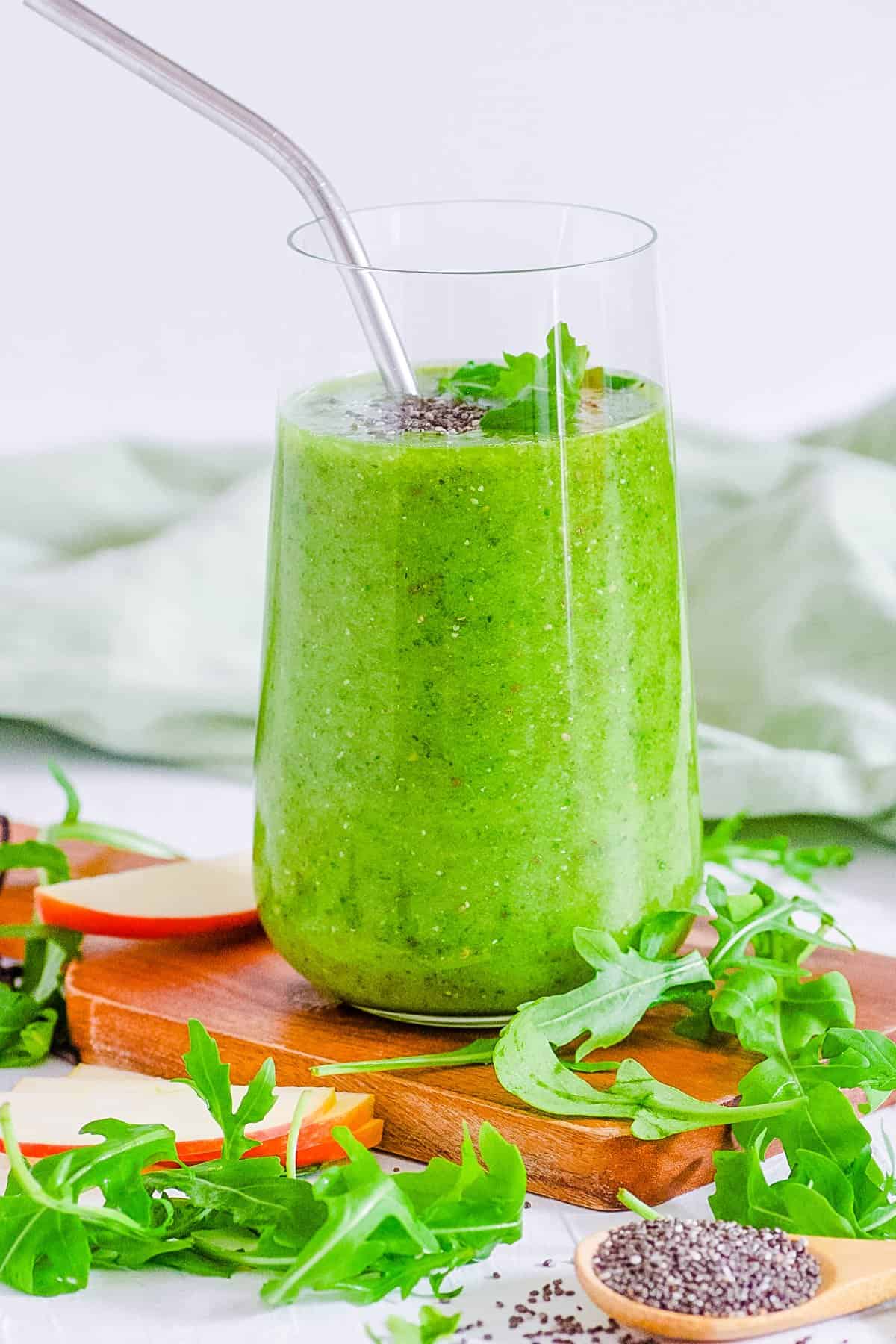easy, healthy, vegan arugula smoothie with banana, apples and mango in a gl، with a straw
