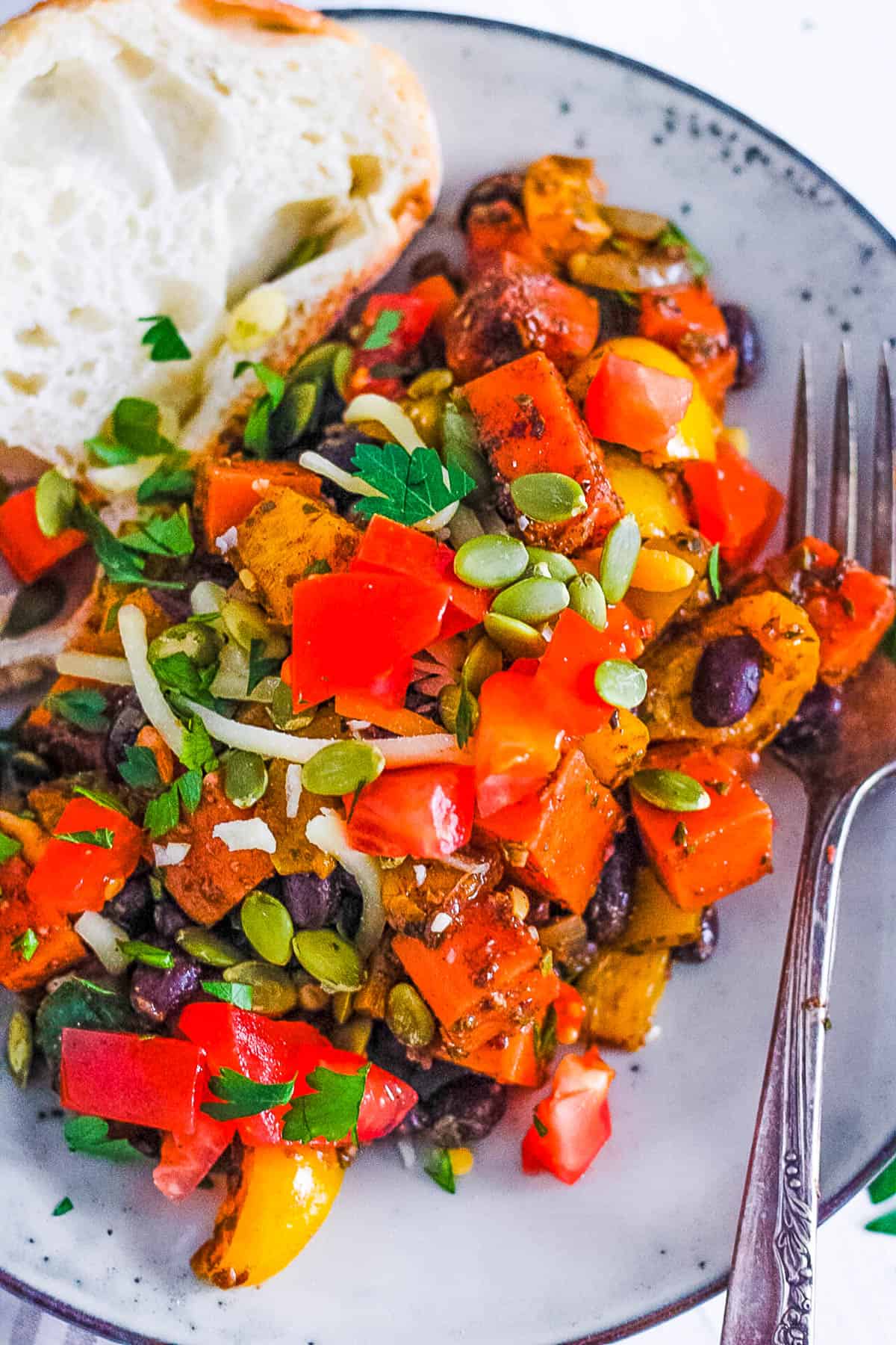 A serving of sweet potato breakfast hash with a piece of toast on a plate with a fork.