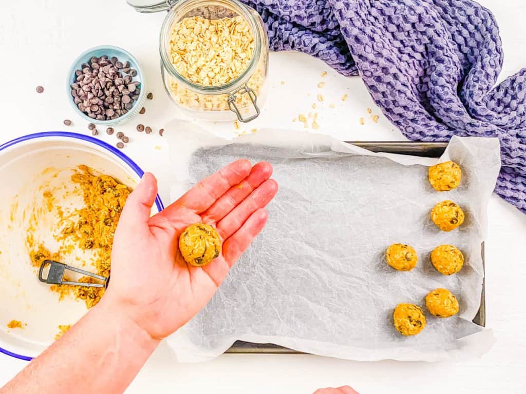 no bake energy balls being rolled and placed on parchment paper