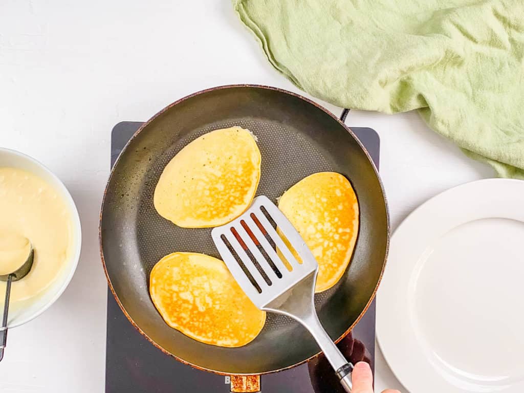 Flipping almond milk pancakes on a skillet.