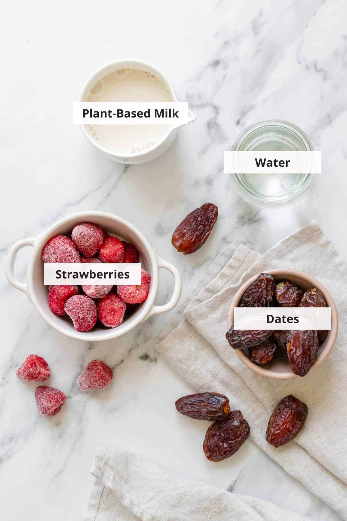 Ingredients for vegan strawberry milk recipe on a white background.