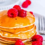 oat milk pancakes stacked on a white plate with raspberries
