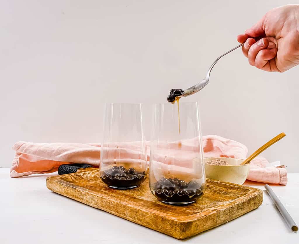 Tapioca pearls being added to a glass.