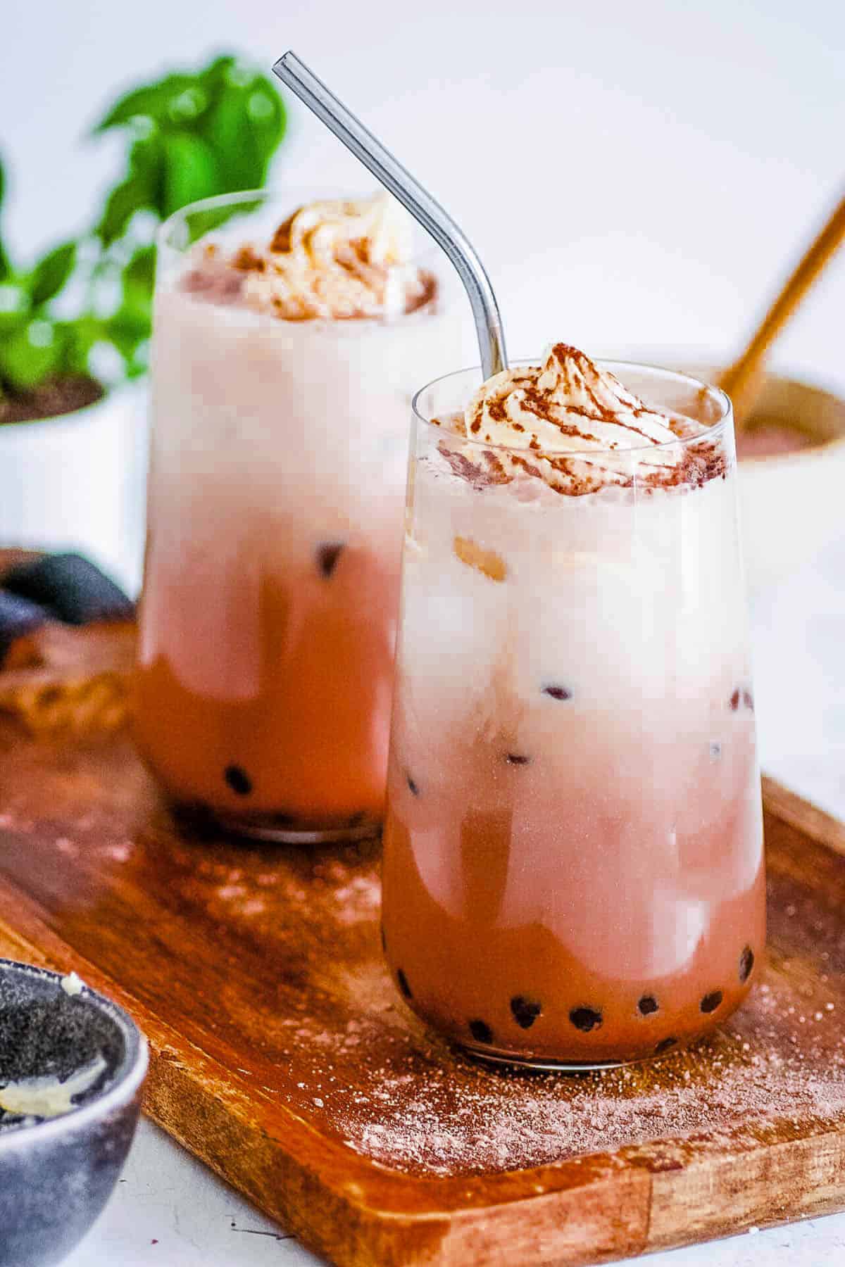 Chocolate milk tea served in two glasses topped with whipped cream.