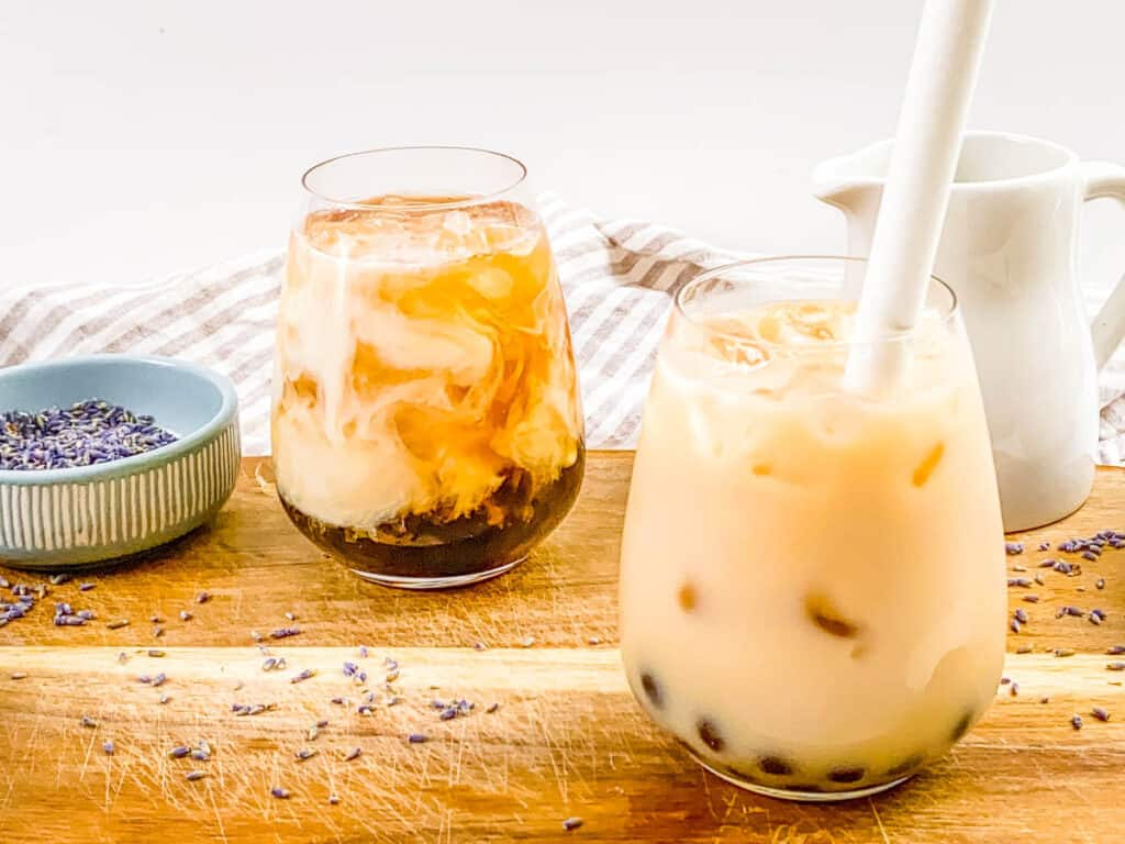 Iced lavender milk tea in a glass with a straw.