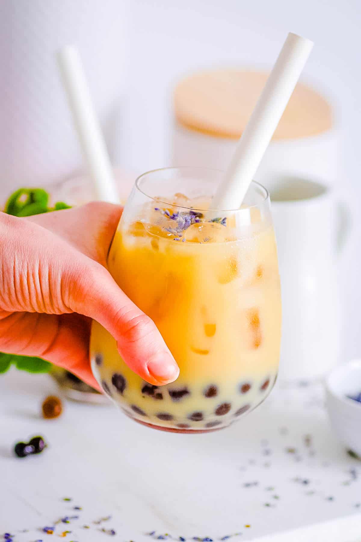 Lavender milk tea with boba in a glass with a straw.