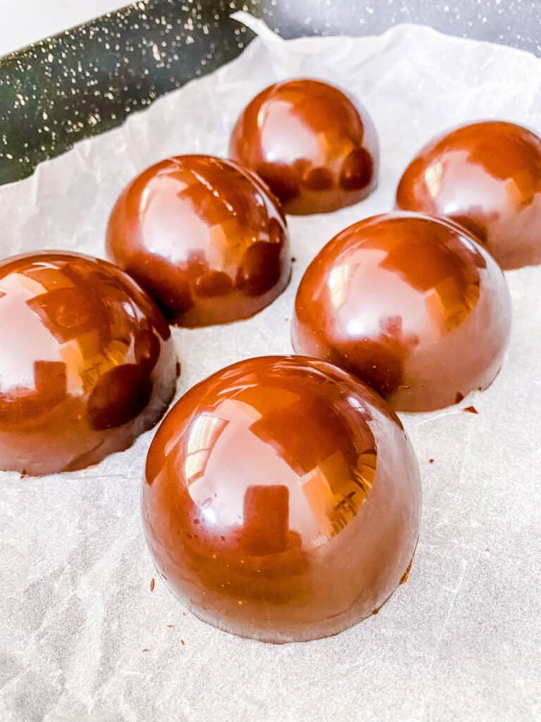 Hot chocolate bomb shells on parchment paper.