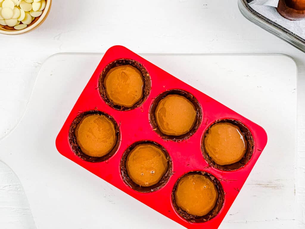 Baileys hot cocoa bomb shells filled with chocolate ganache in a silicone mold.