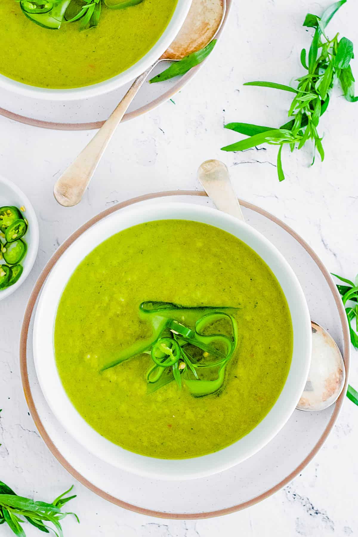 Cucumber gazpacho topped with fresh herbs in a white bowl.