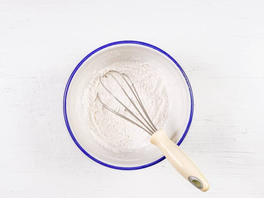 Dry ingredients for donuts mixed in a bowl.