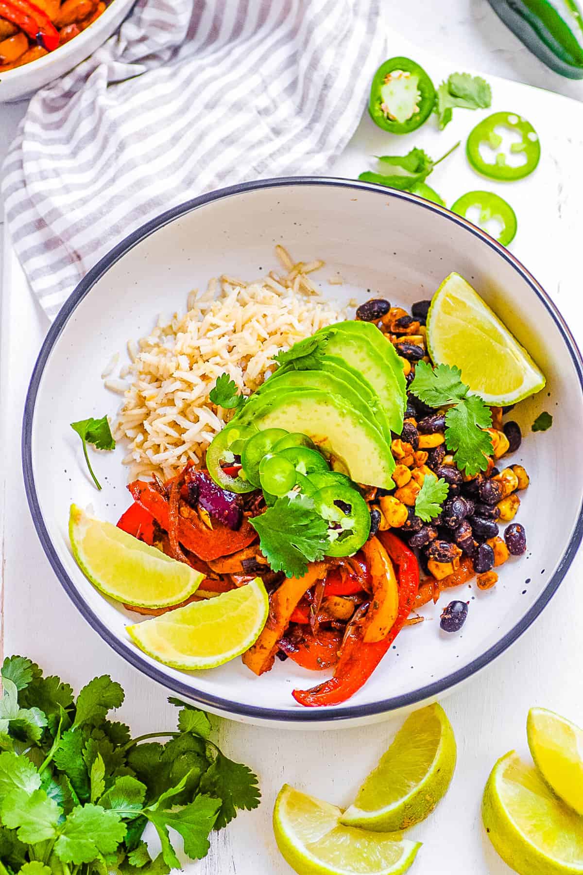 Vegetarian fajita bowl with avocado and lime, on a white background.