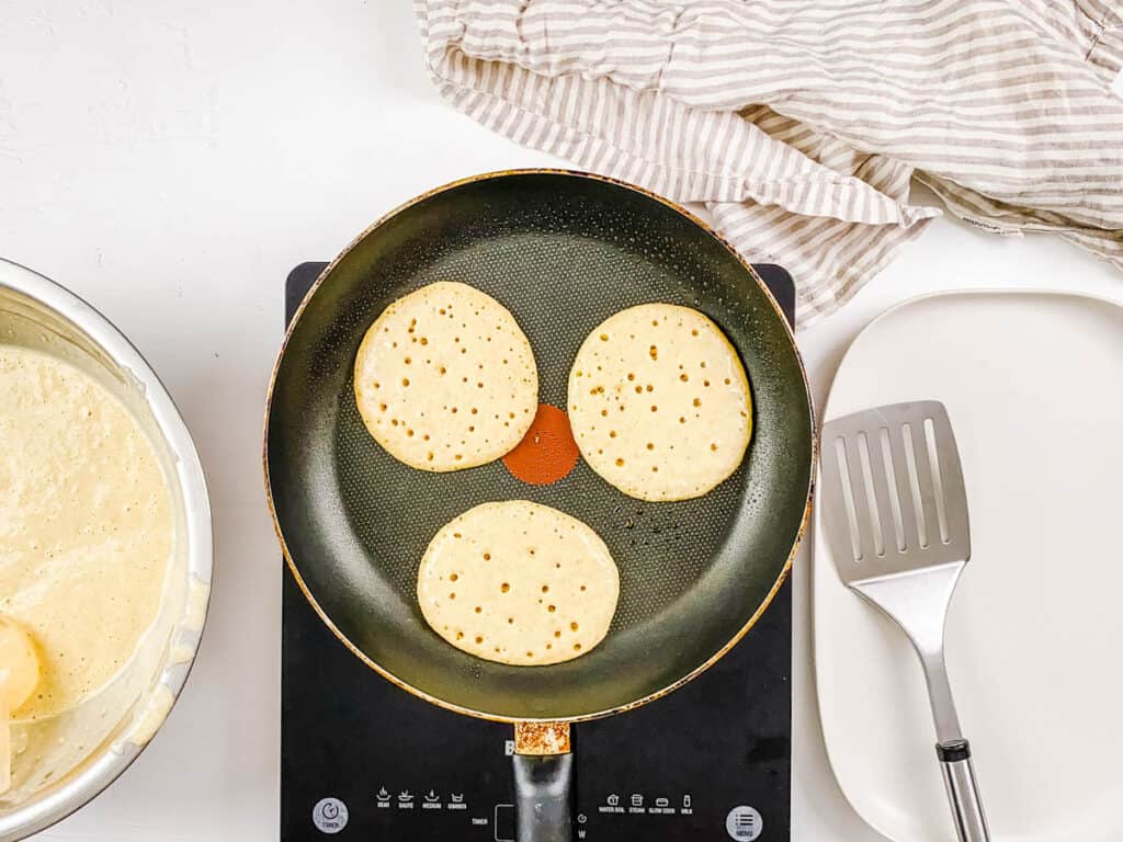 Sourdough pancakes made with leftovers sourdough starter discard cooking in a skillet.