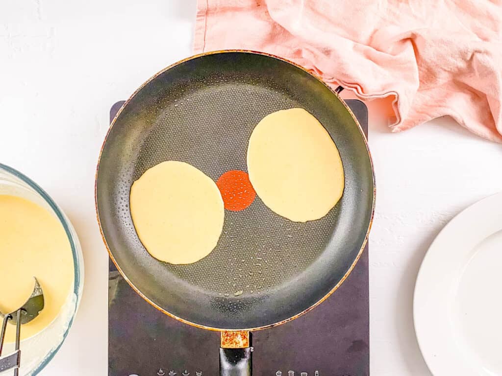 Pancake batter cooking in a pan.