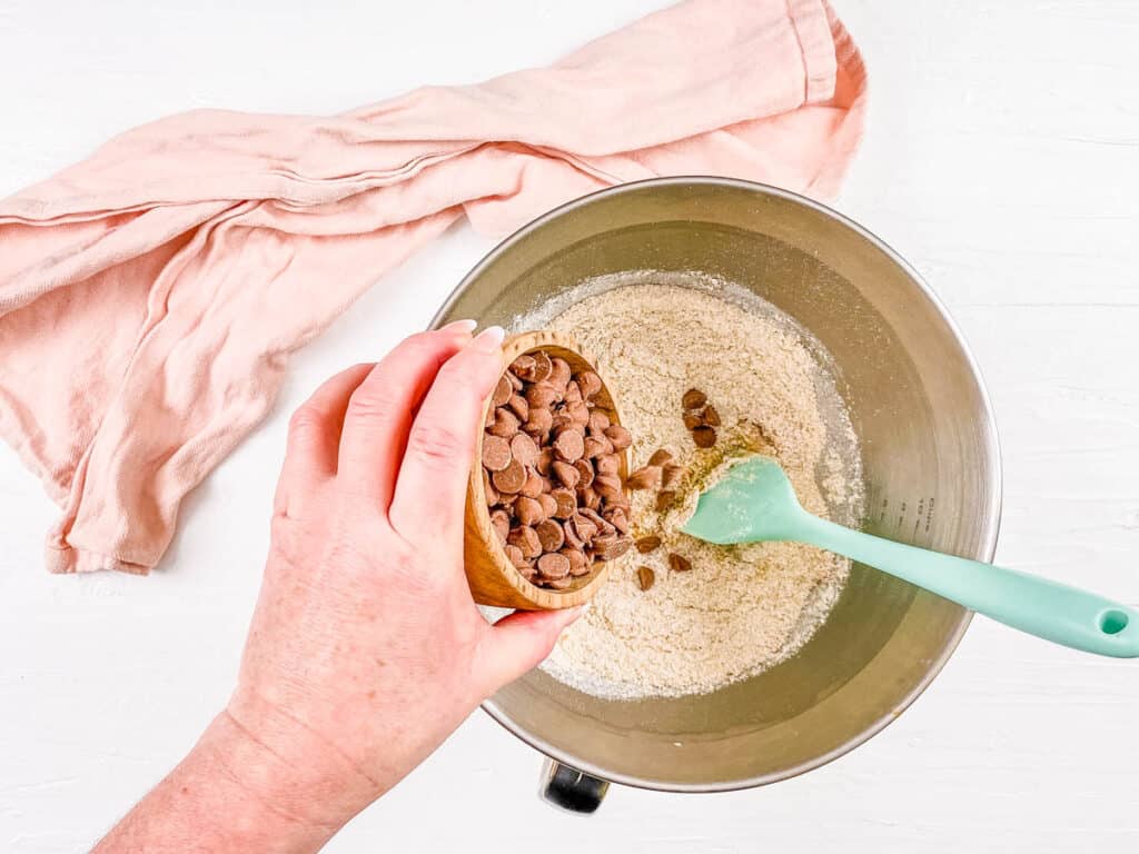 Chocolate chips combined with dry ingredients for cookie batter preparation.