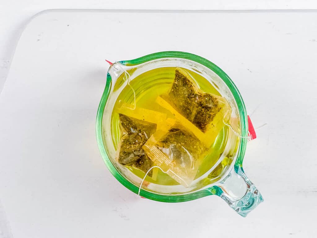 Green tea bags steeping in a glass.