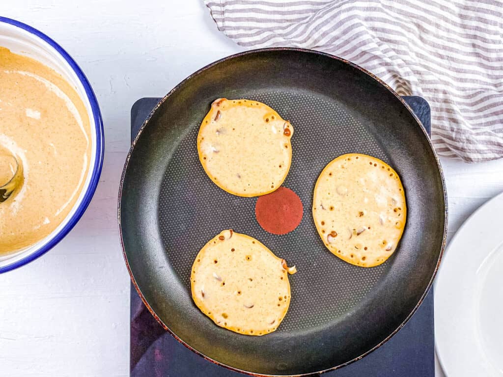 Pancakes cooking in a skillet.