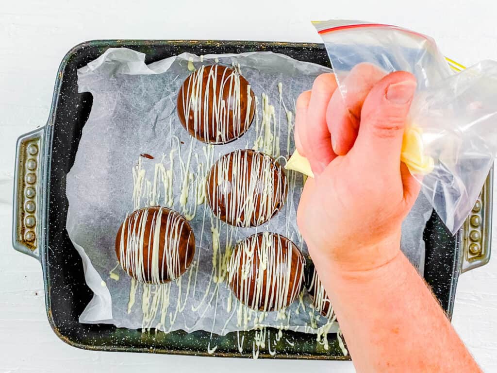 Baileys irish cream chocolate bombs dressed with icing on a baking sheet.