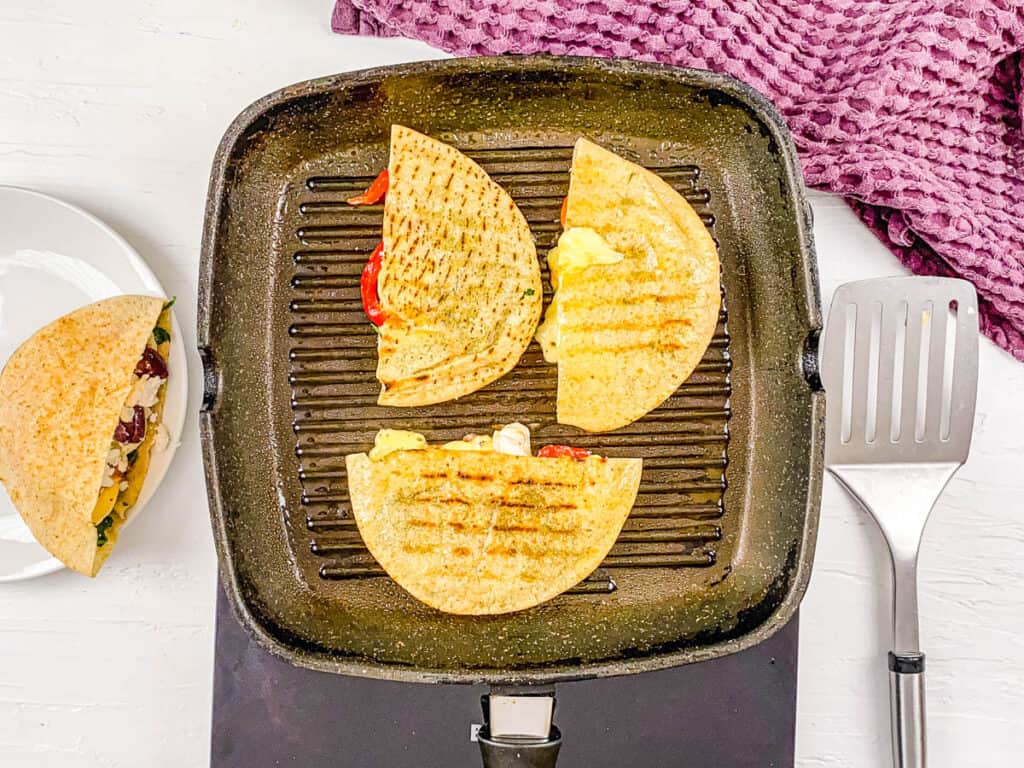 Pita grilled cheese sandwiches cooking on a grill pan.