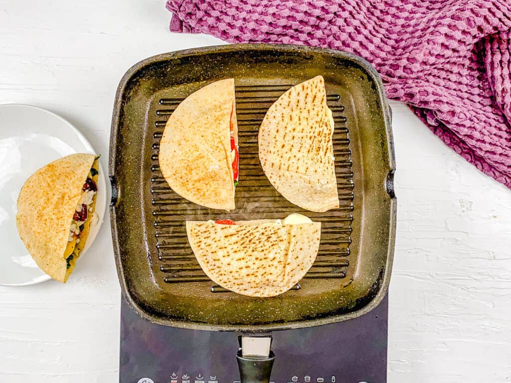 Grilled cheese pita sandwiches cooking on a grill pan.