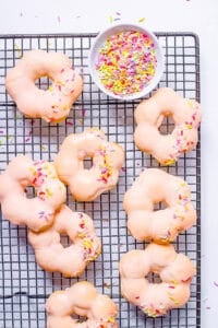 Baked mochi donuts with vegan glaze and sprinkles on a wire rack.