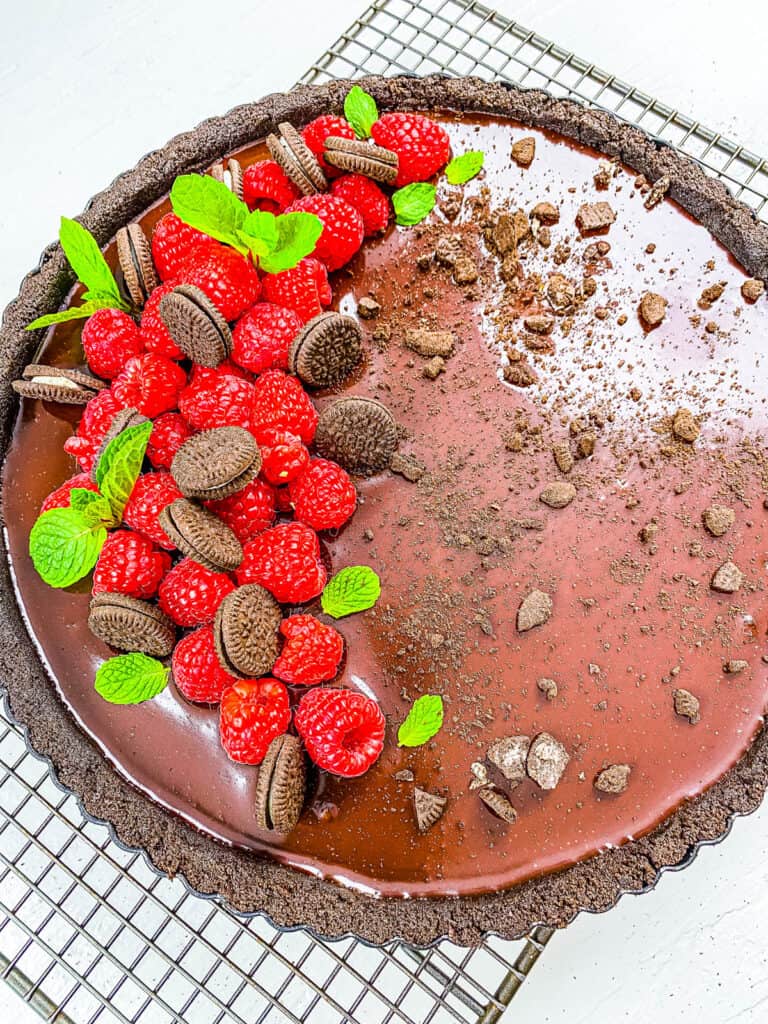 No bake Oreo pie topped with berries and mini Oreos on a wire rack.