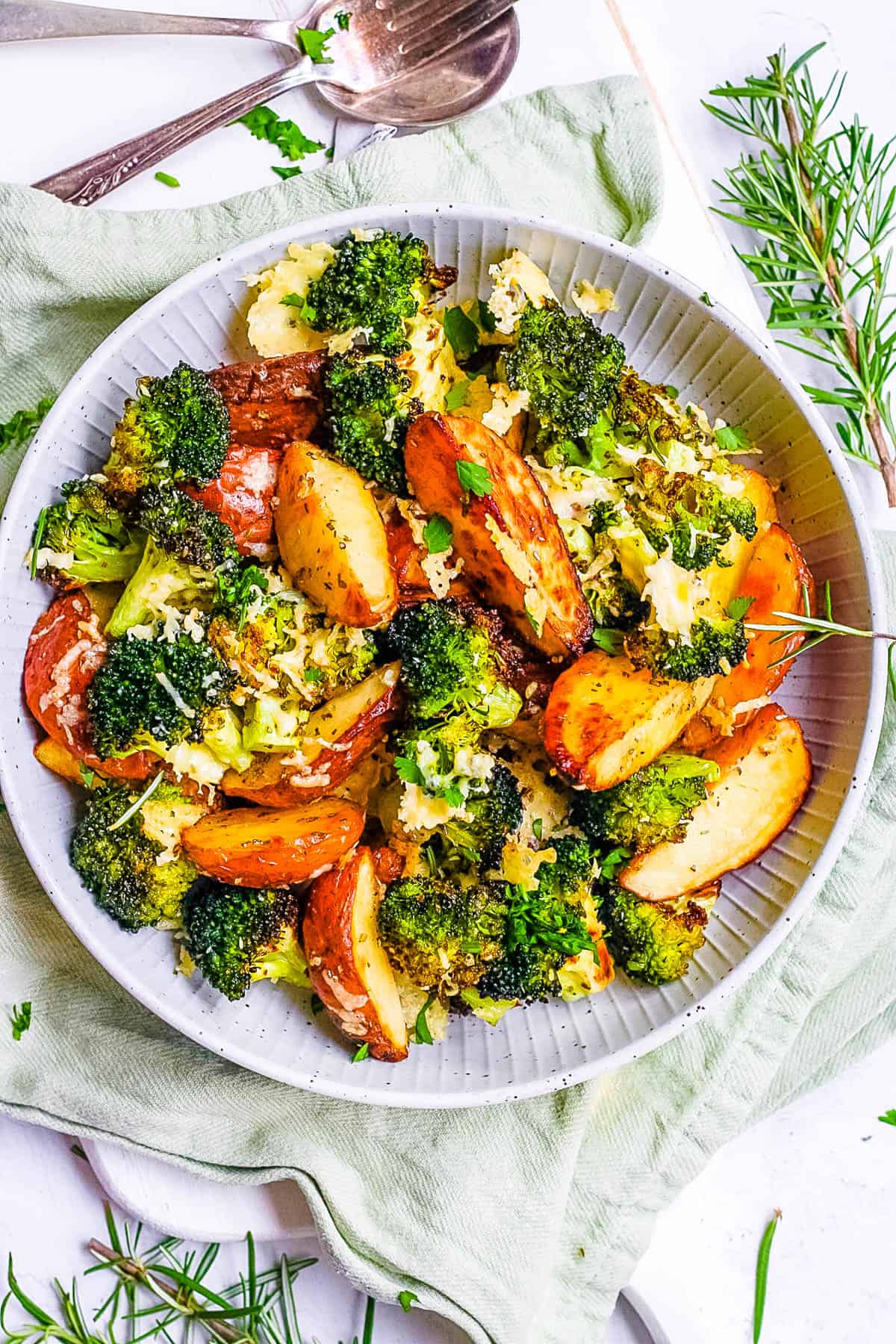 Oven roasted broccoli and potatoes with parmesan and garlic in a serving bowl.