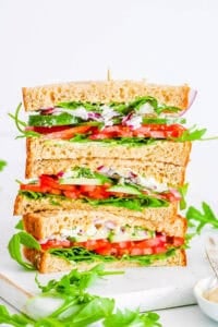 Copycat Panera mediterranean veggie sandwiches stacked on a white cutting board.